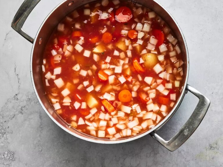 Overhead shot of a pot with broth and vegetables cooking for albondigas
