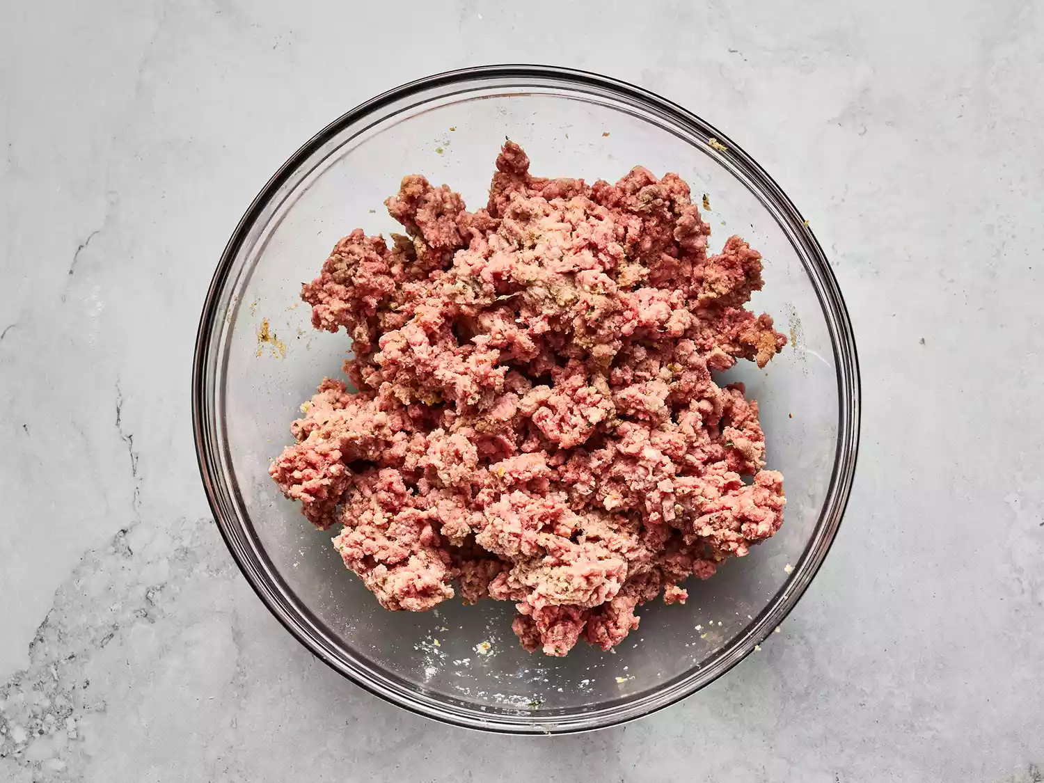 Overhead shot of ground meat in a mixing bowl for meatballs