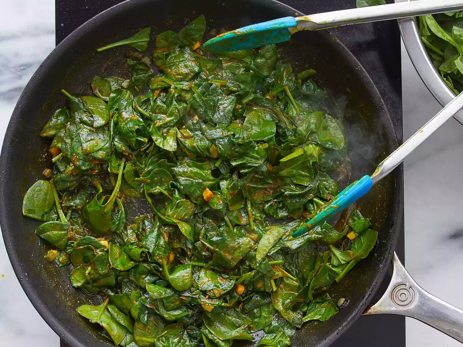 Spinach and mustard greens cooking in large skillet