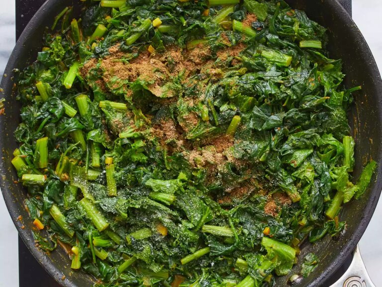 Ground cumin and coriander atop cooked greens in large skillet