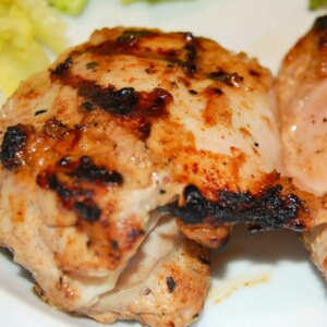 Close up view of a grilled chicken thigh tandoori on a white plate