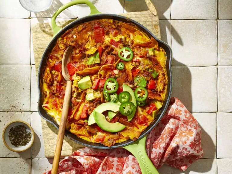 Cast iron skillet with mexican migas topped with jalapenos and avocado