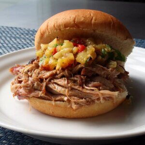 Close up view of pineapple pulled pork al pastor with pineapple relish on a bun, on a white plate