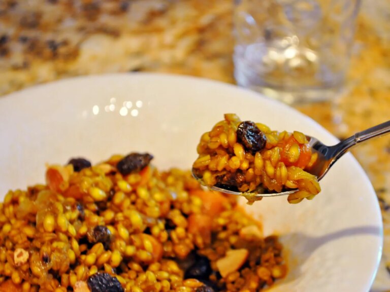 Close up view of indian curried barley pilaf on a white plate and on a fork