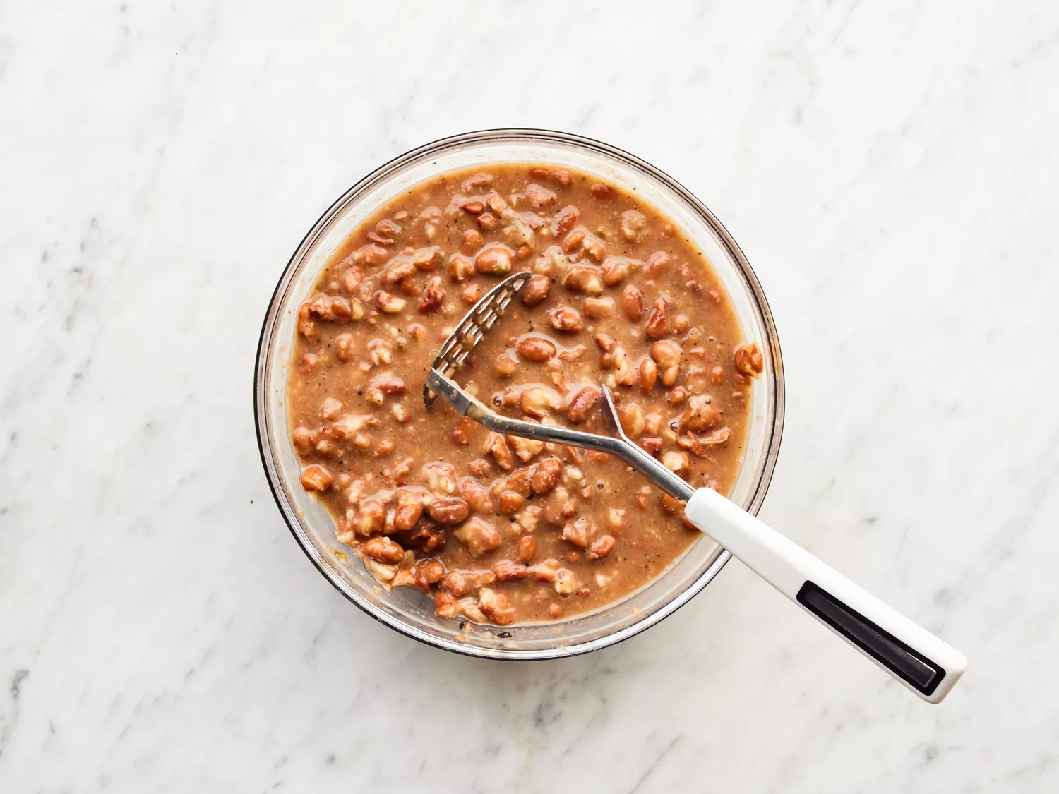 beans mashed in a large bowl with some of the cooking liquid. 