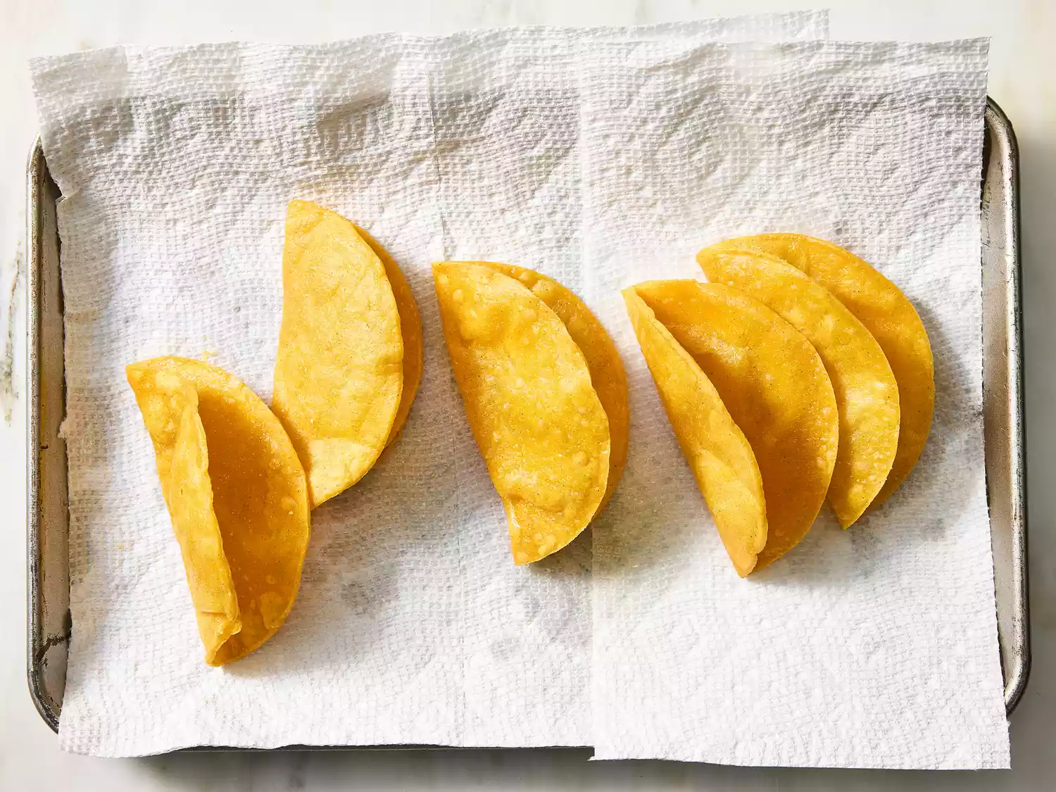 Fried taco shells resting on paper towels to drain excess oil.