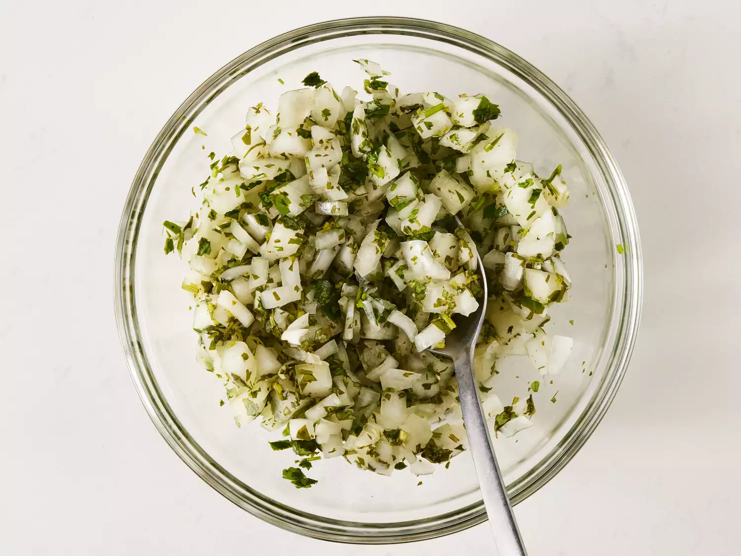 an overhead shot of onion relish with a spoon in a glass bowl