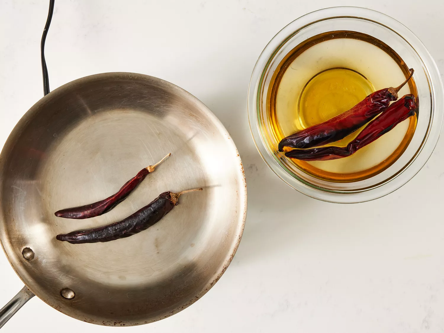 an overhead shot of chile pods toasting in a skillet and two chile pods soaking in a bowl