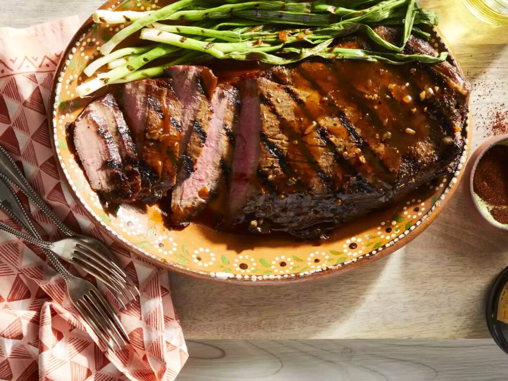 Marinated flank steak on platter with grilled green onions
