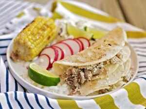 Pulled pork tacos in tortilla with radishes and corn on the cob