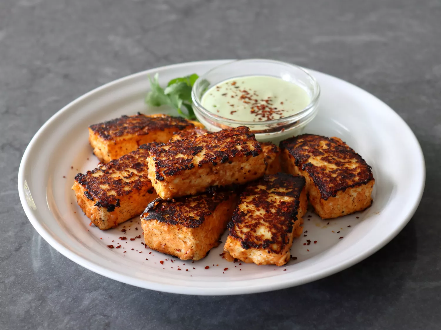 Homemade paneer with spices and dip on white plate