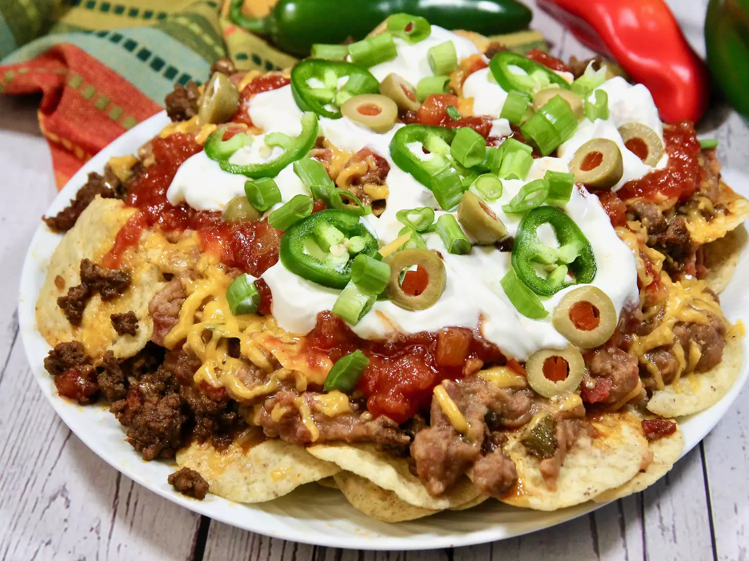 Loaded beef nachos topped with sour cream, jalapenos and olives