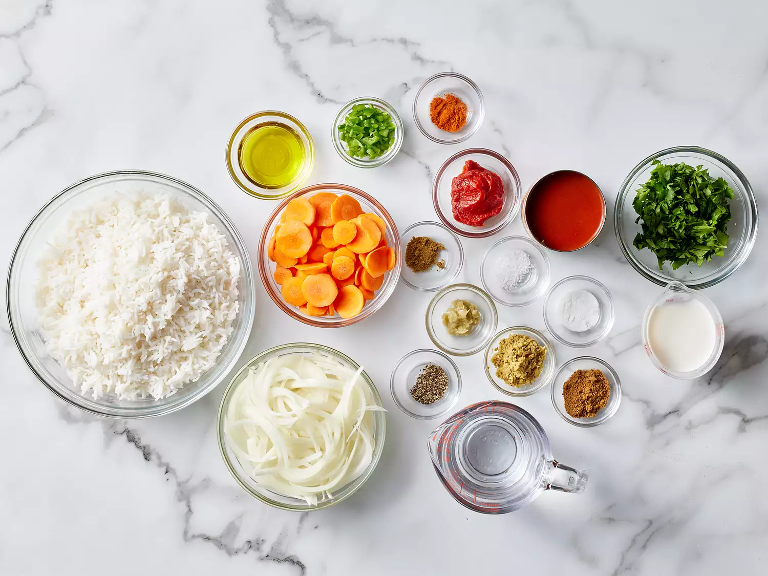 all ingredients for a chick pea masala gathered in glass bowls on a marble countertop. 