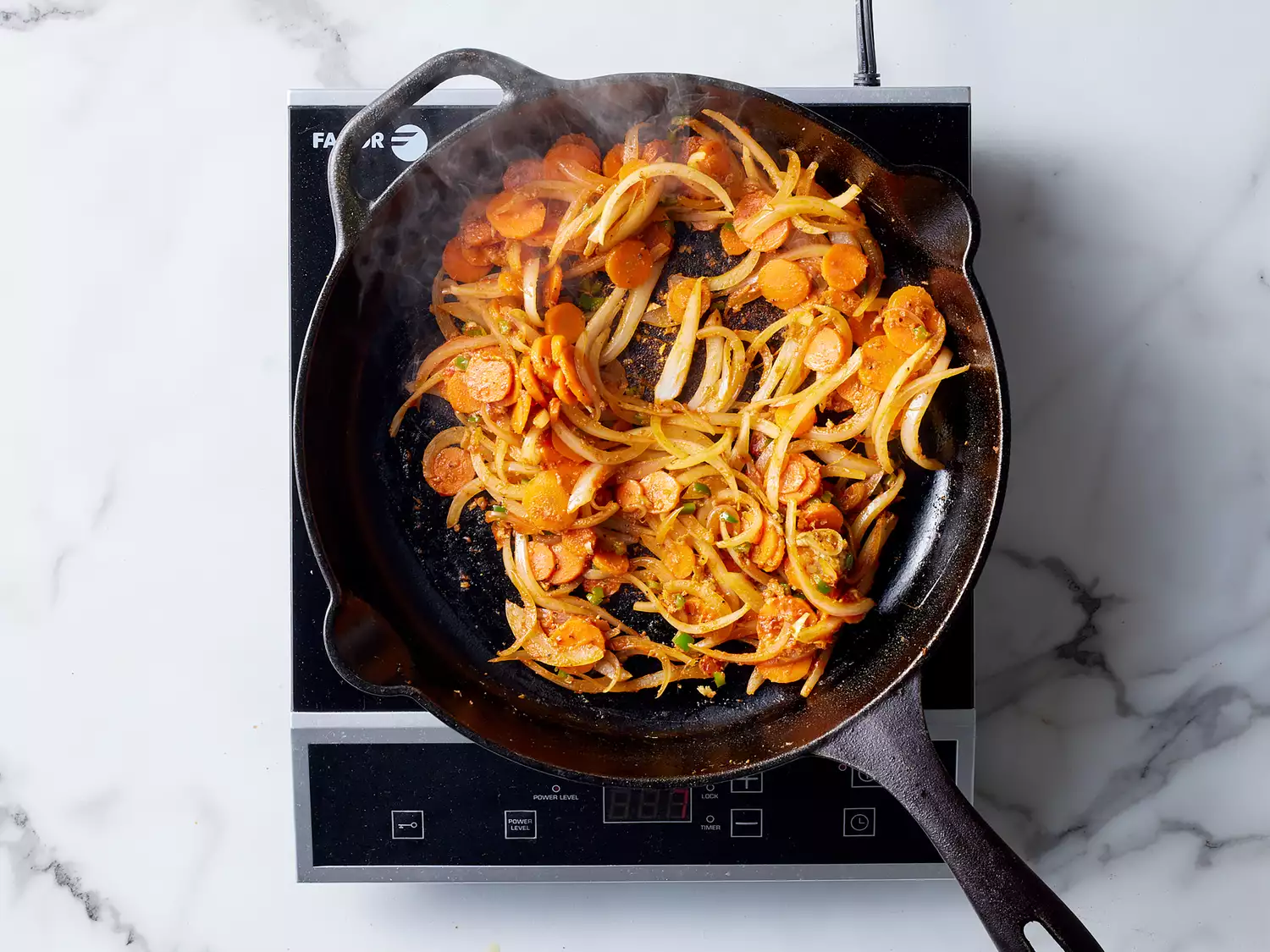 seasoning combined with onions and carrots in a cast iron skillet. 