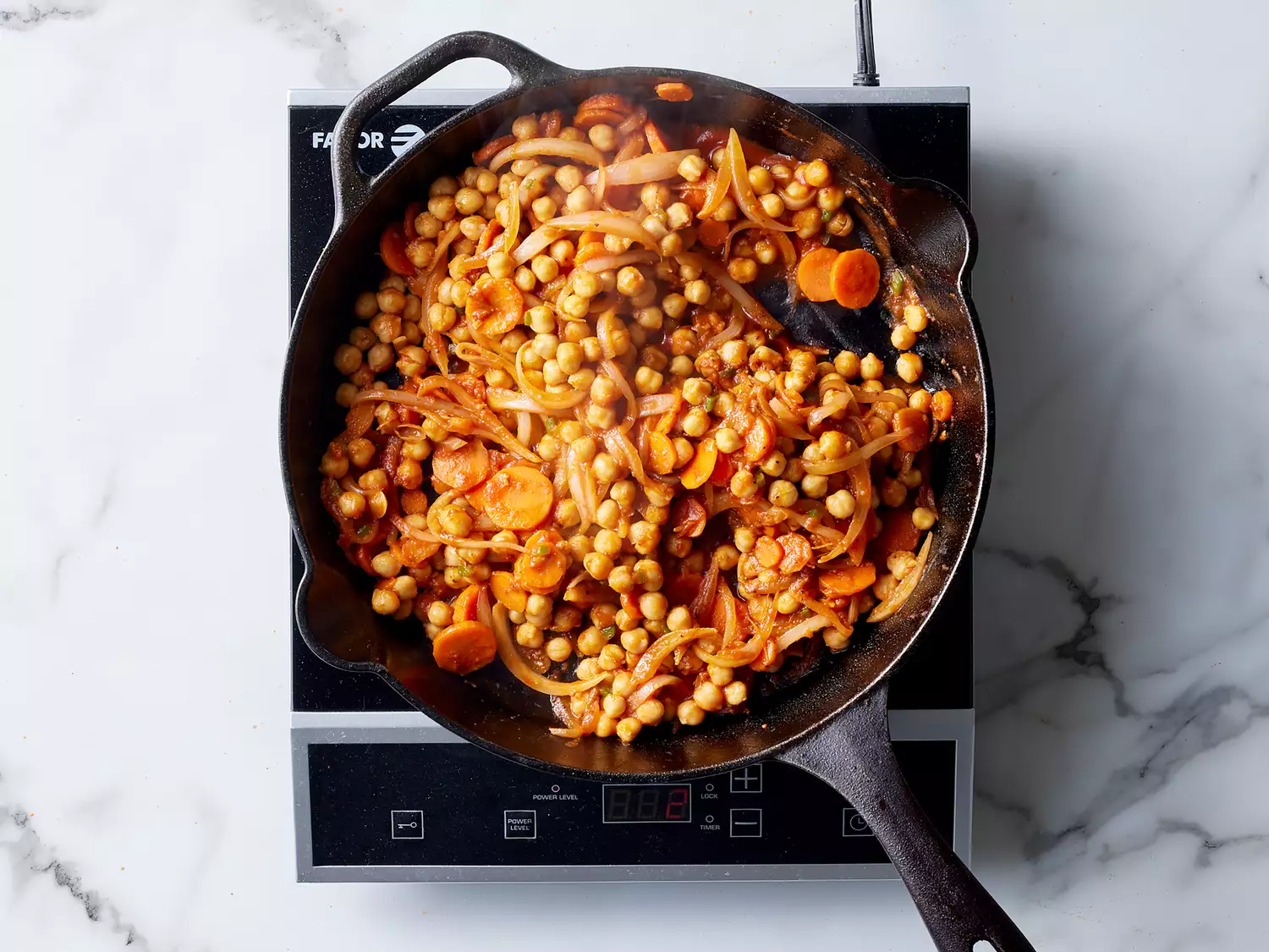 chick peas added to seasoned carrots and onions in a cast iron skillet. 