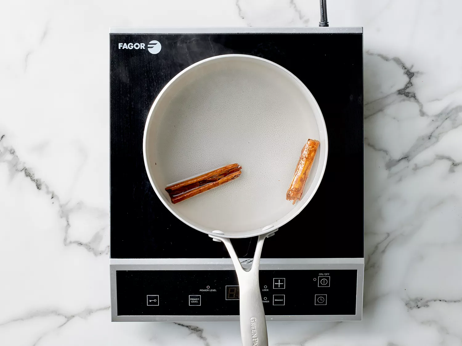 two cinnamon sticks being steeped in simmering water. 