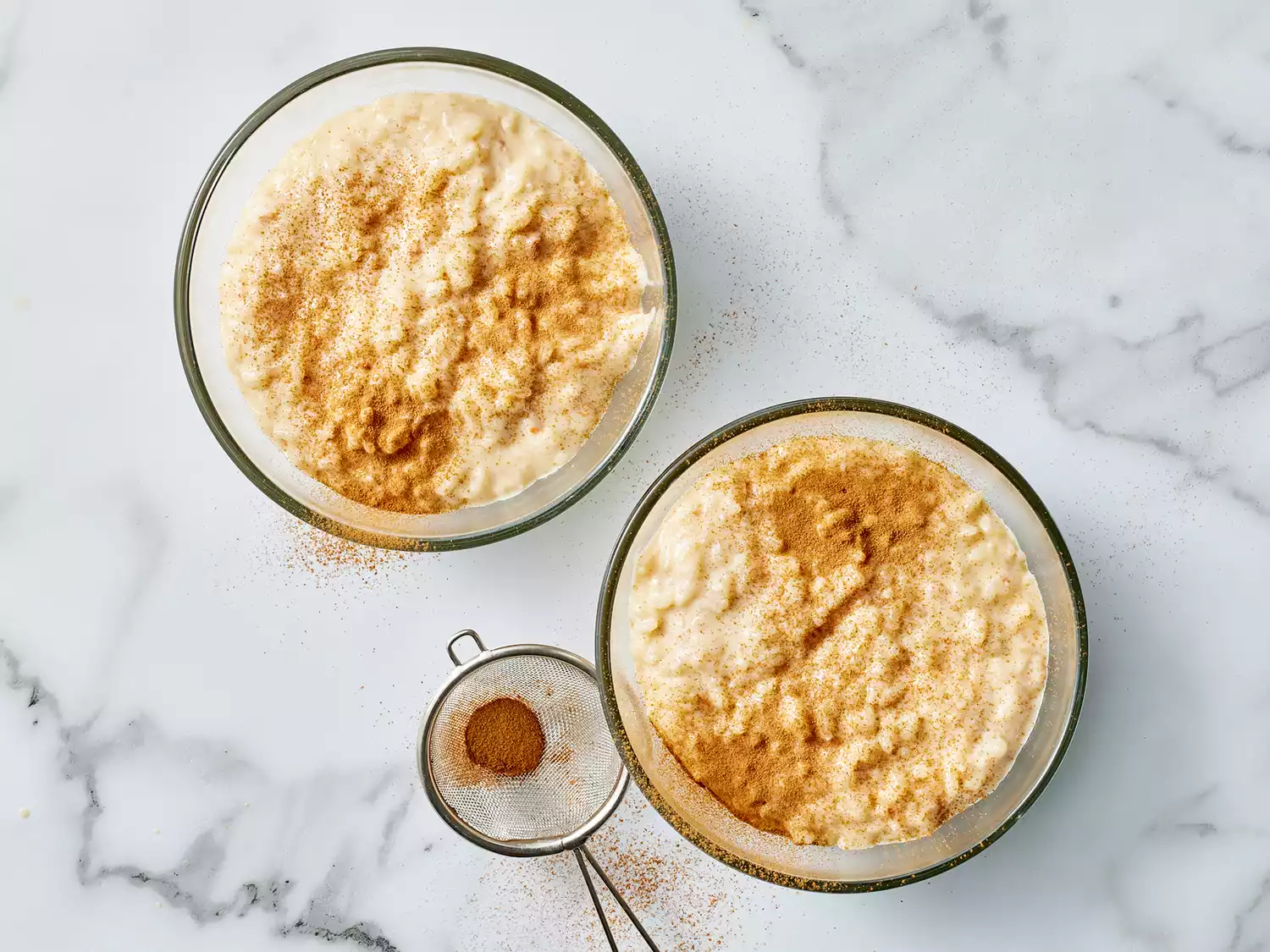 an overhead view of two bowls of creamy arroz con leche dusted with cinnamon. 