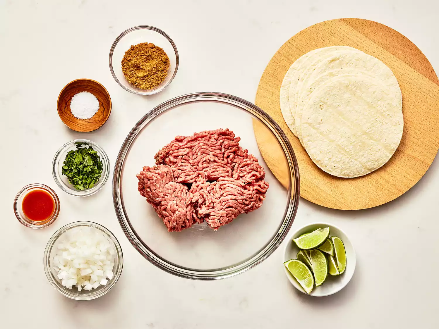 an overhead view of all ingredients to make fried beef tacos, gathered on a kitchen counter.