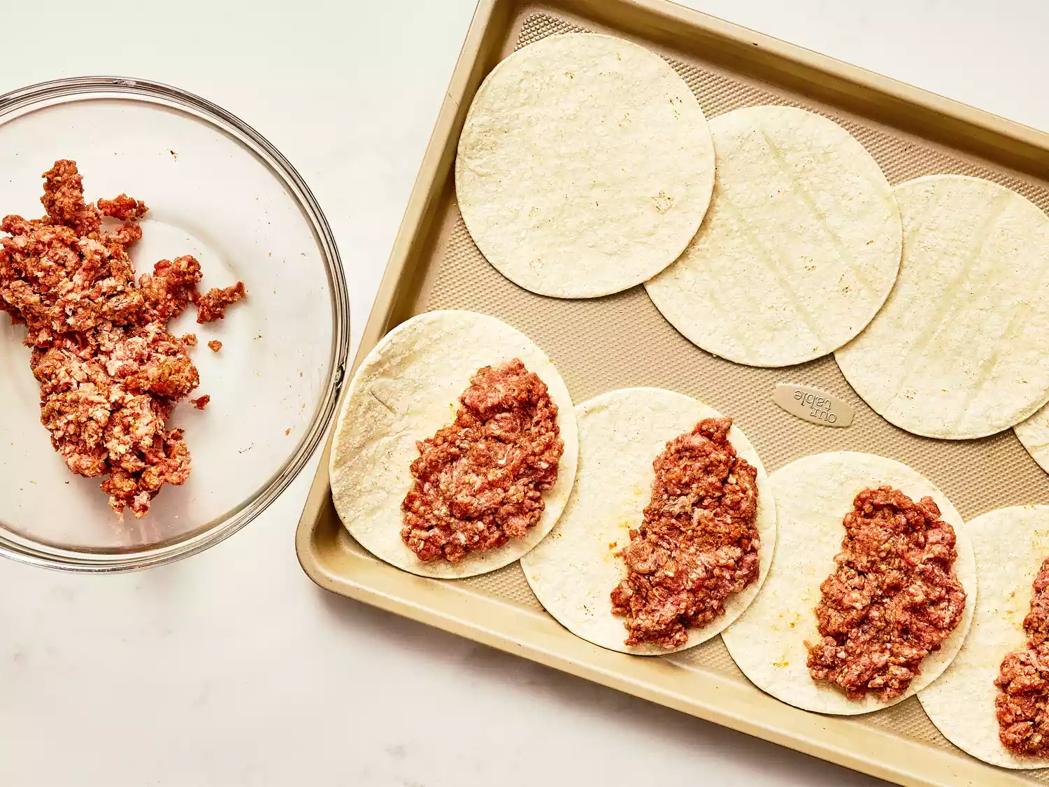 seasoned ground beef pressed into one half of each of the 8 flour tortillas on a baking sheet. 