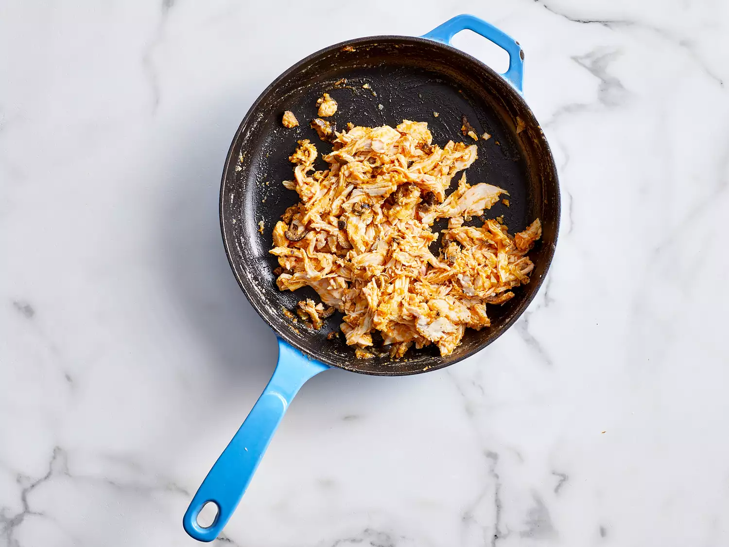 Overhead view of a pan with cooked shredded chicken 
