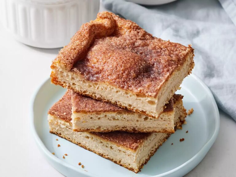 A stack of three churro cheesecake bars on a blue plate.