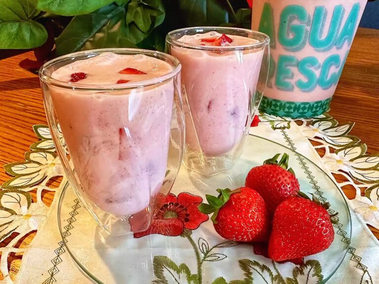 Clear glasses with creamy strawberry drink with whole strawberries on the side
