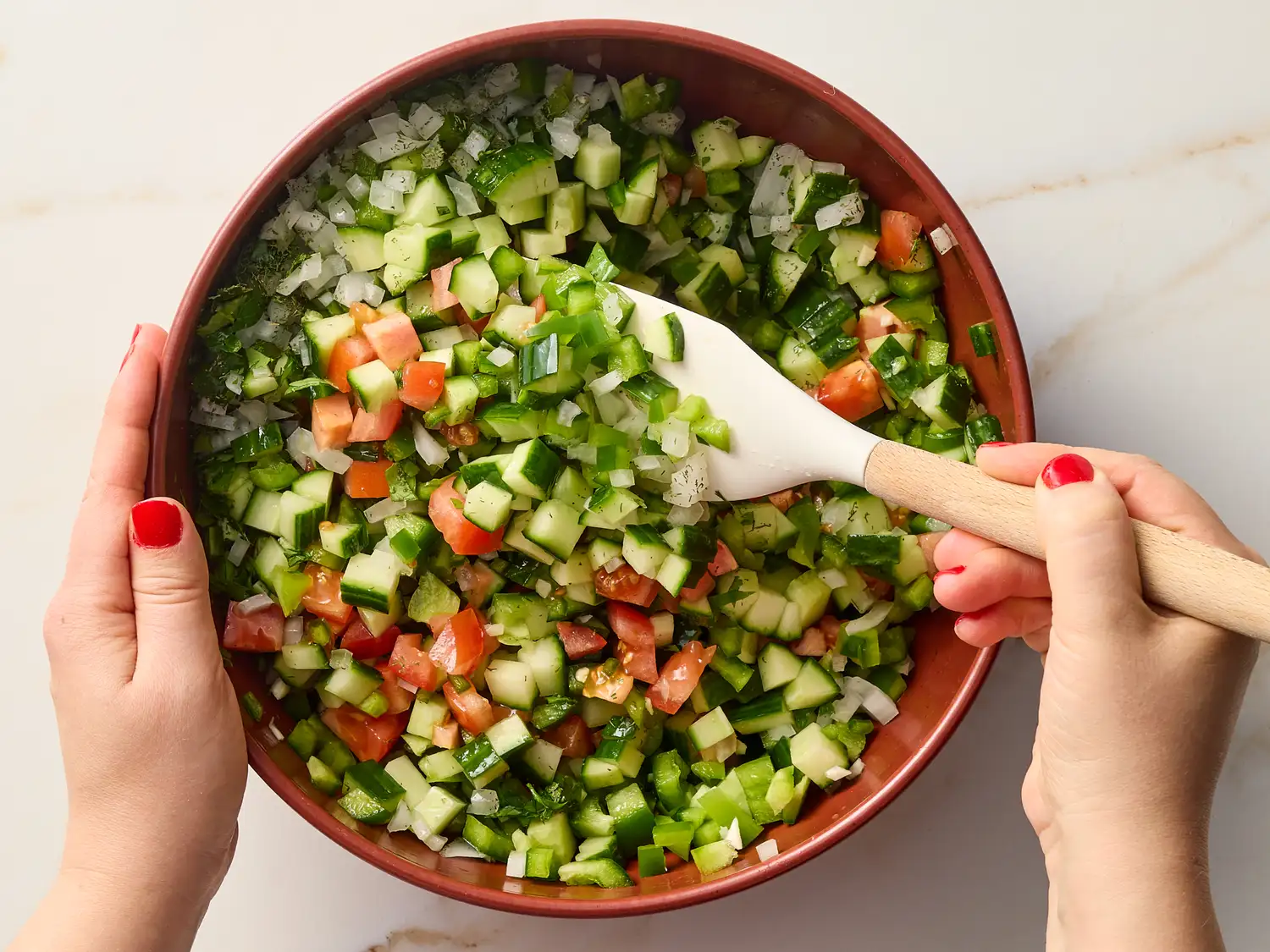 Mixing cucumber salsa with a white spatula in a bowl