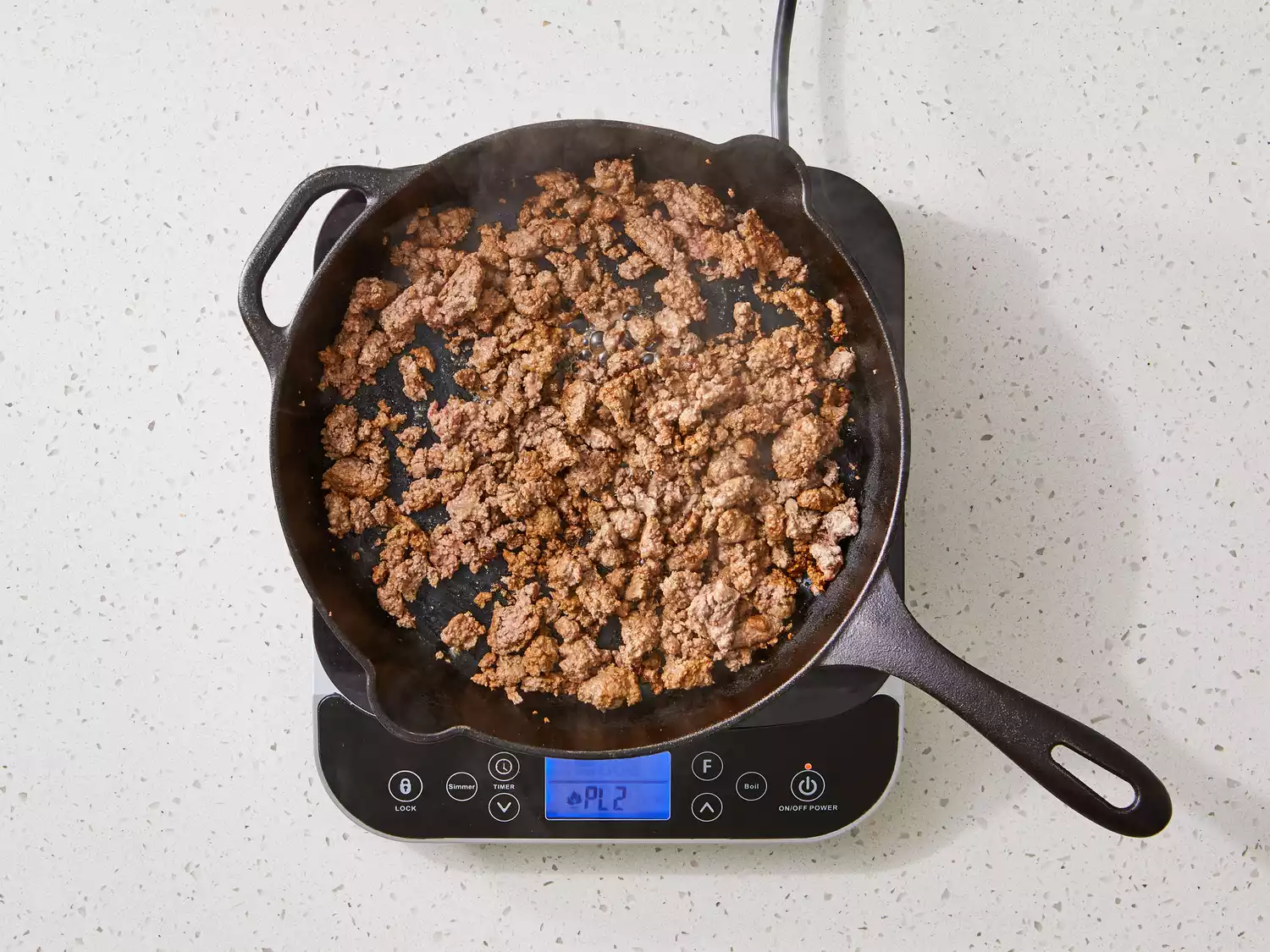 ground beef browning in a cast iron skillet.