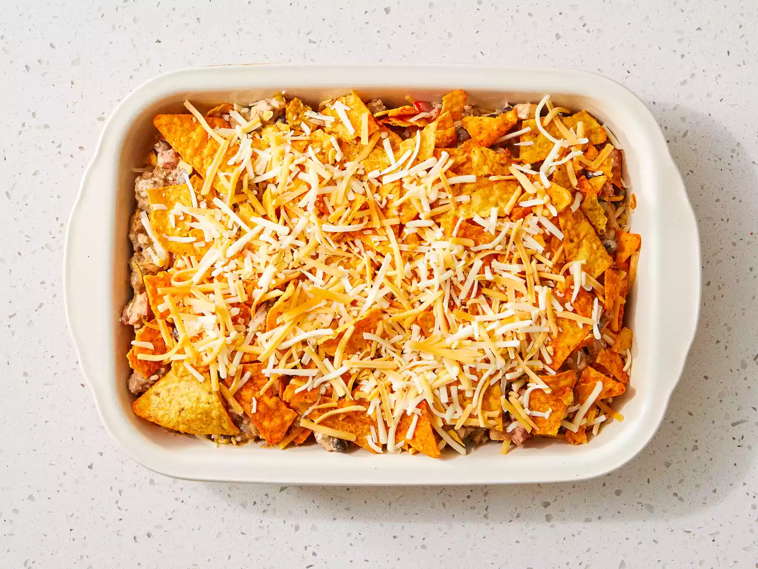 Dorito casserole layers repeated to fill dish ending with a layer of shredded cheese