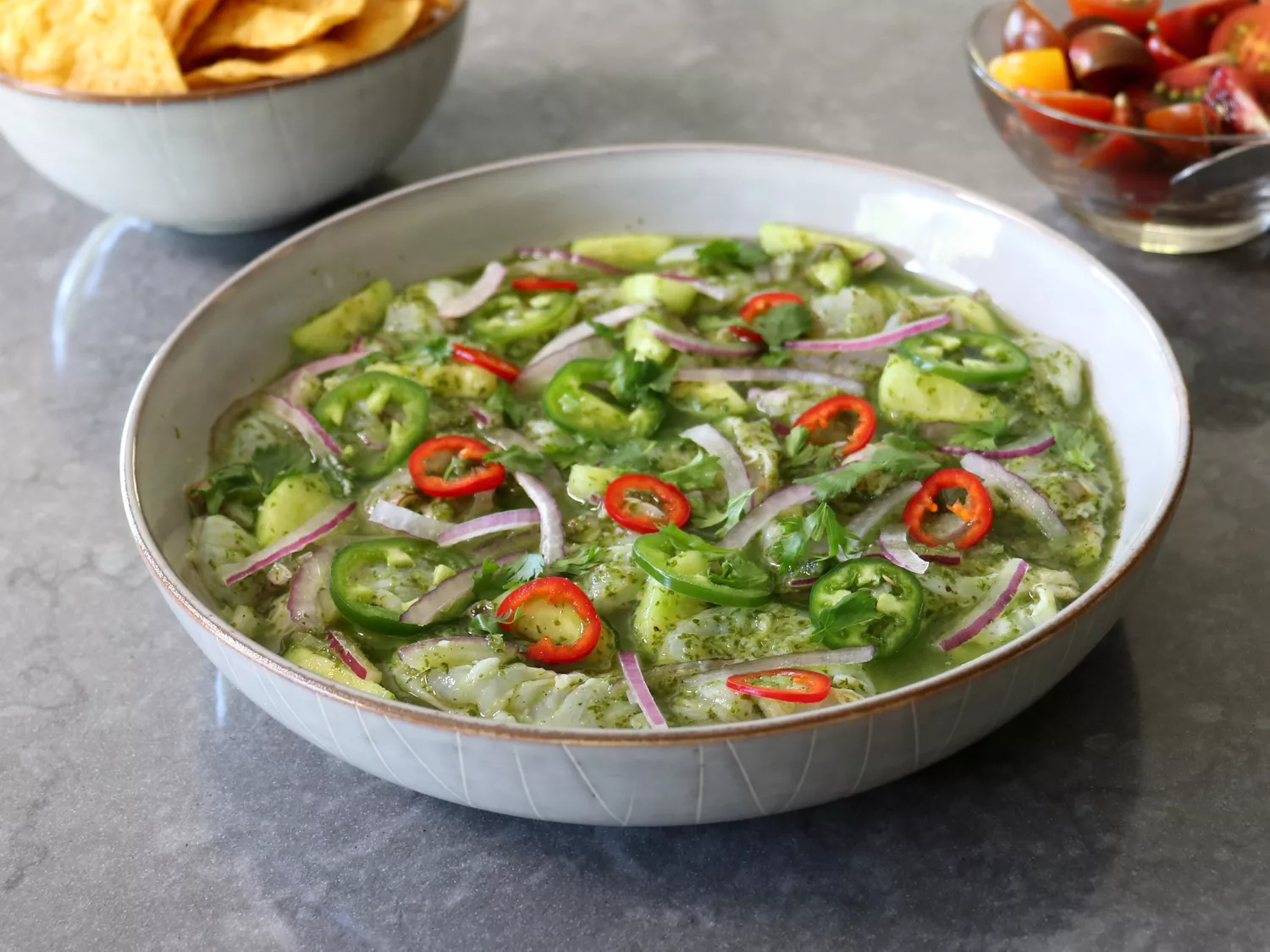White ceramic bowl of shrimp aguachile, or chile and lime water with red onion, shrimp, and cilantro