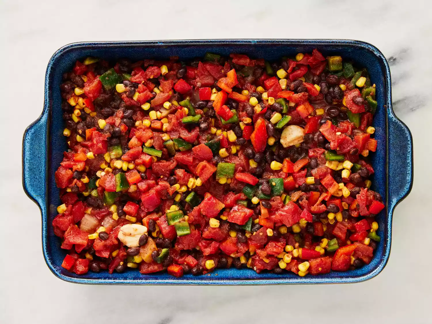 Tomatoes, beans, corn, peppers, seasonings and garlic poured over chicken and rice. 