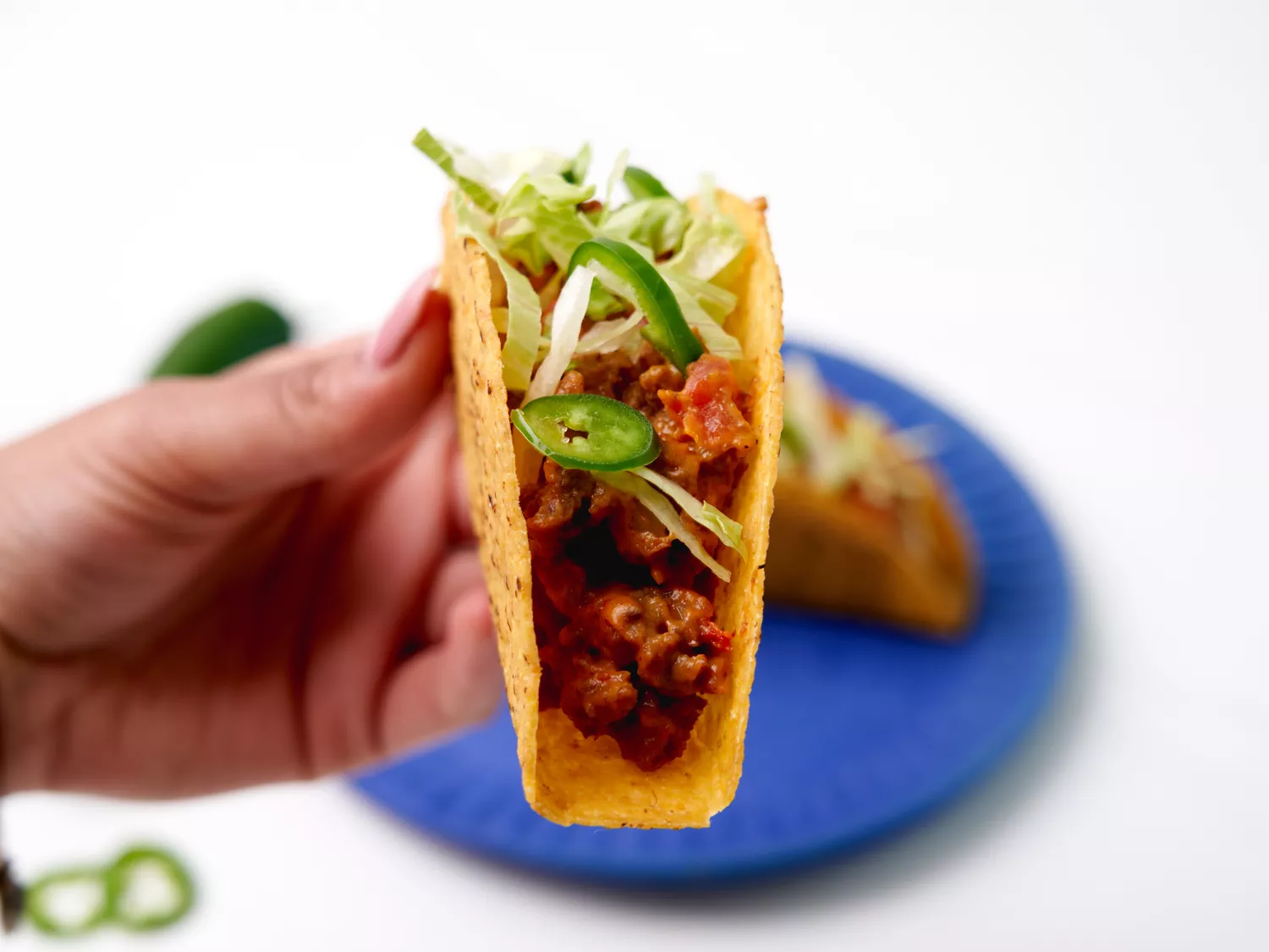 Close up of tacos filled with ground beef topped with lettuce and jalapenos