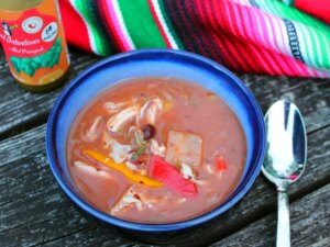 Chicken taco soup in blue bowl with mexican fabric in background