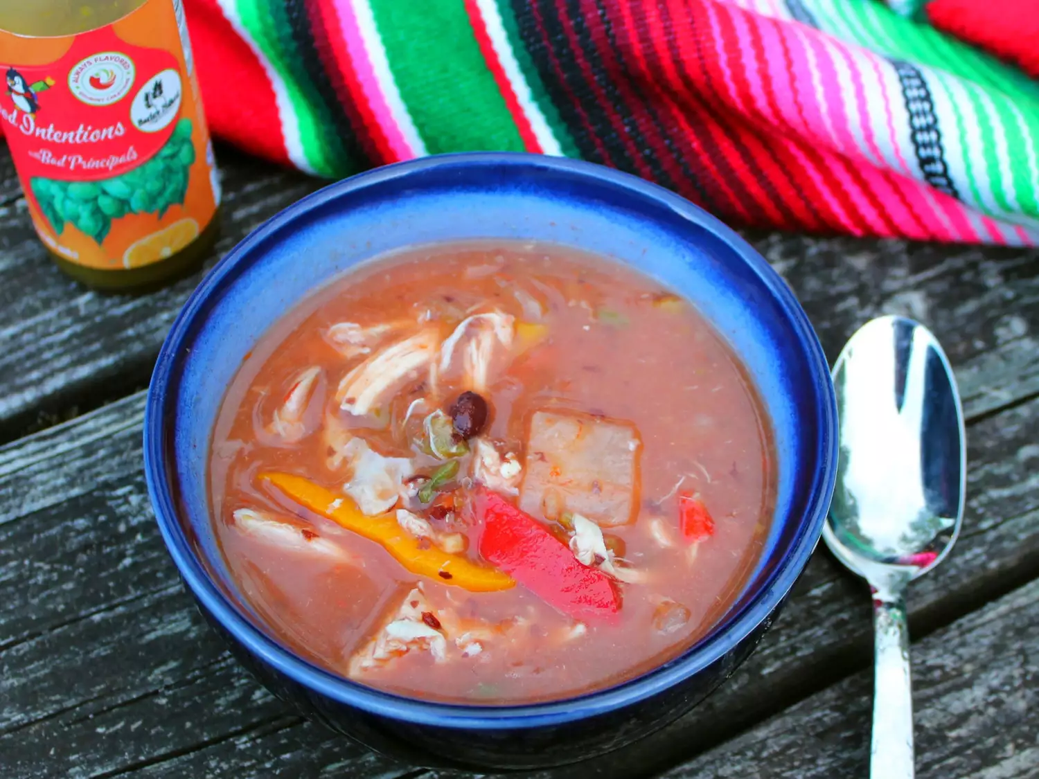 Chicken taco soup in blue bowl with mexican fabric in background