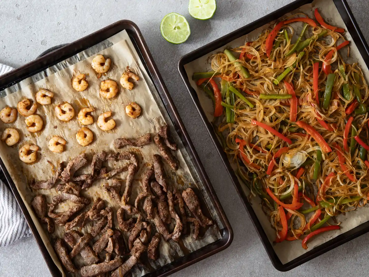 Sheet pans filled with cooked steak shrimp and sauted vegetables