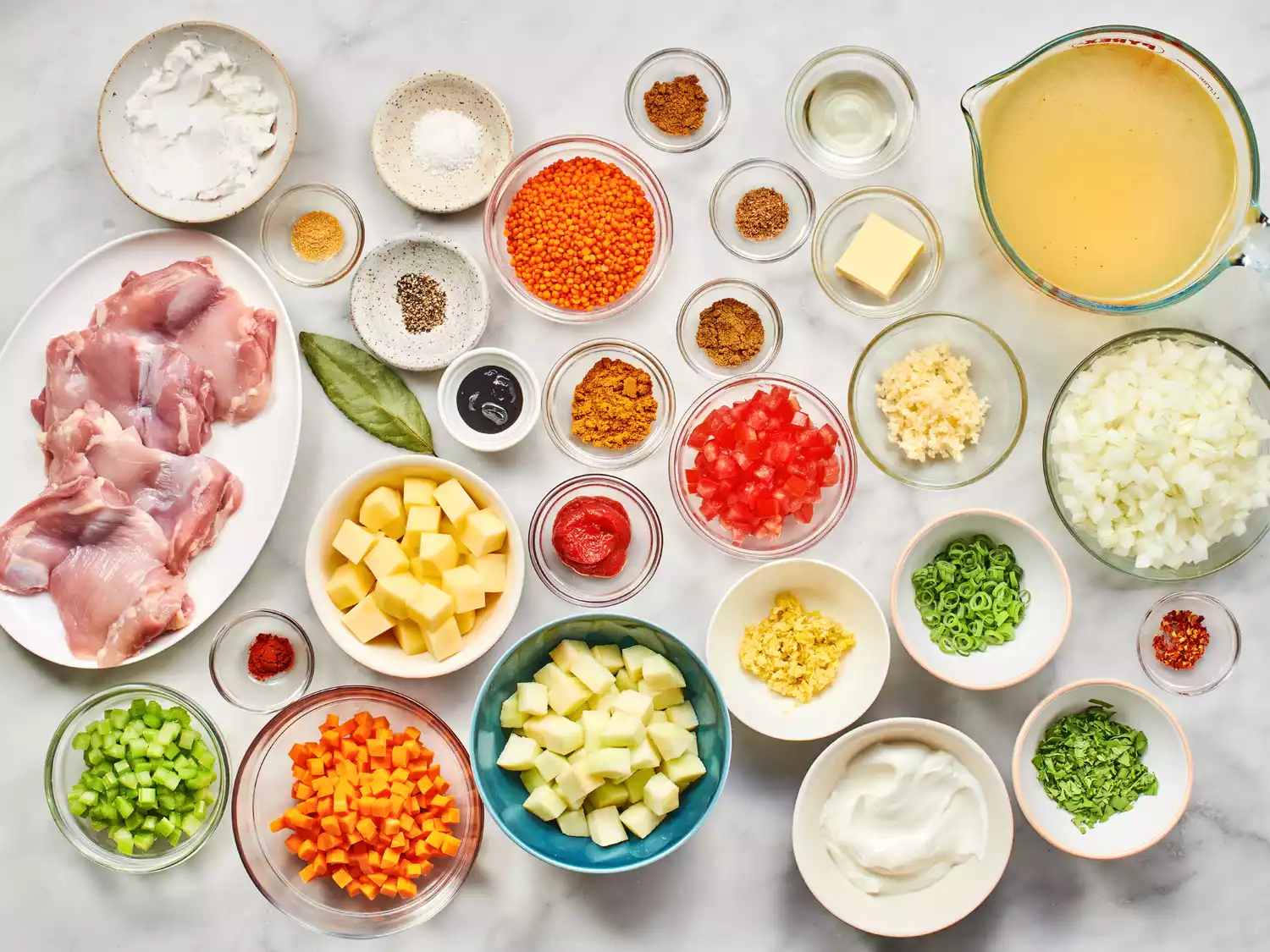 Various bowls and plates filled with ingredients to make Mulligatawny Soup.