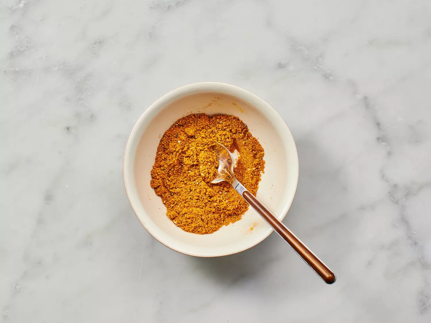 Spices in a bowl with a spoon.