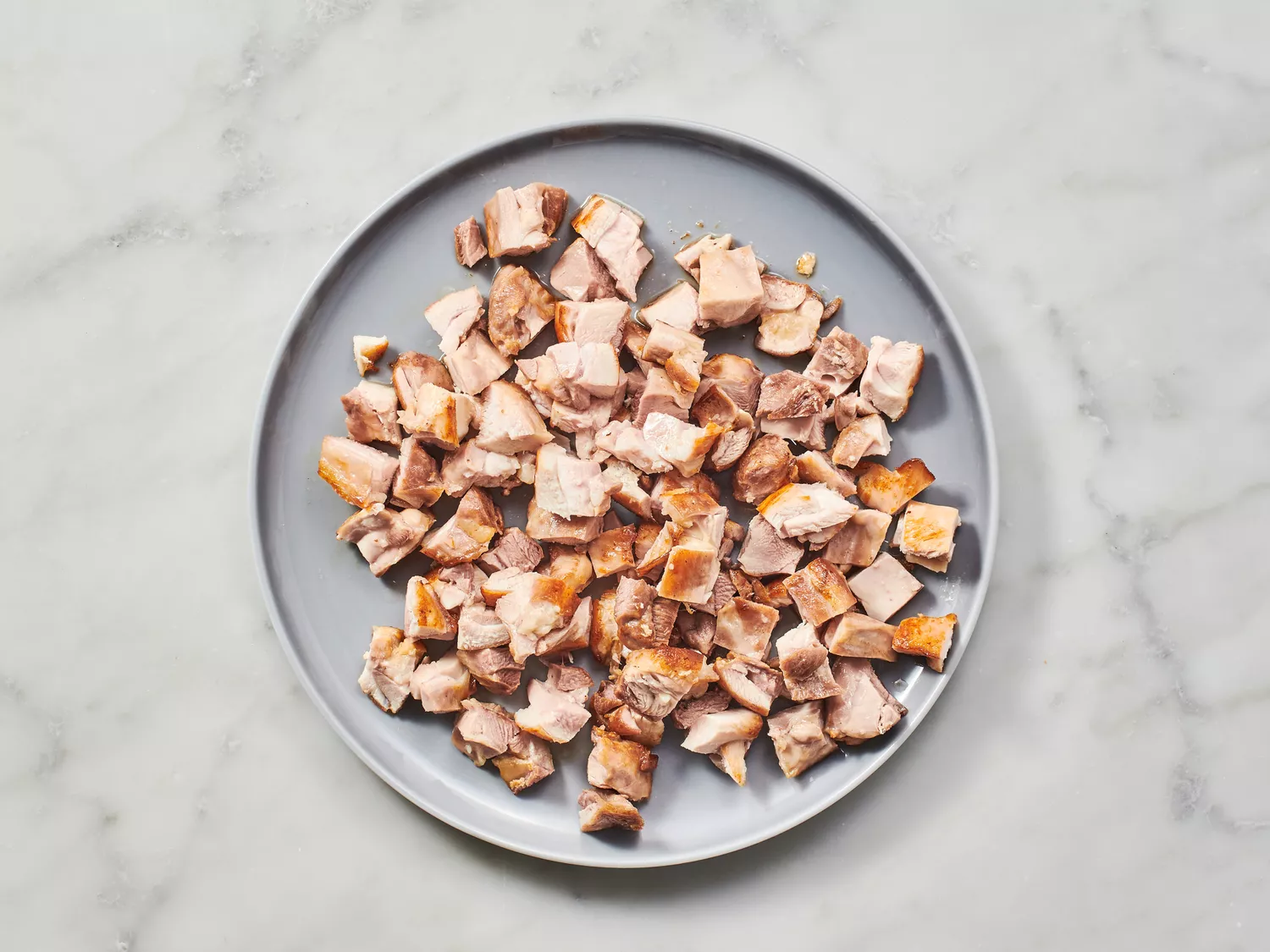 Diced chicken thighs on a plate.