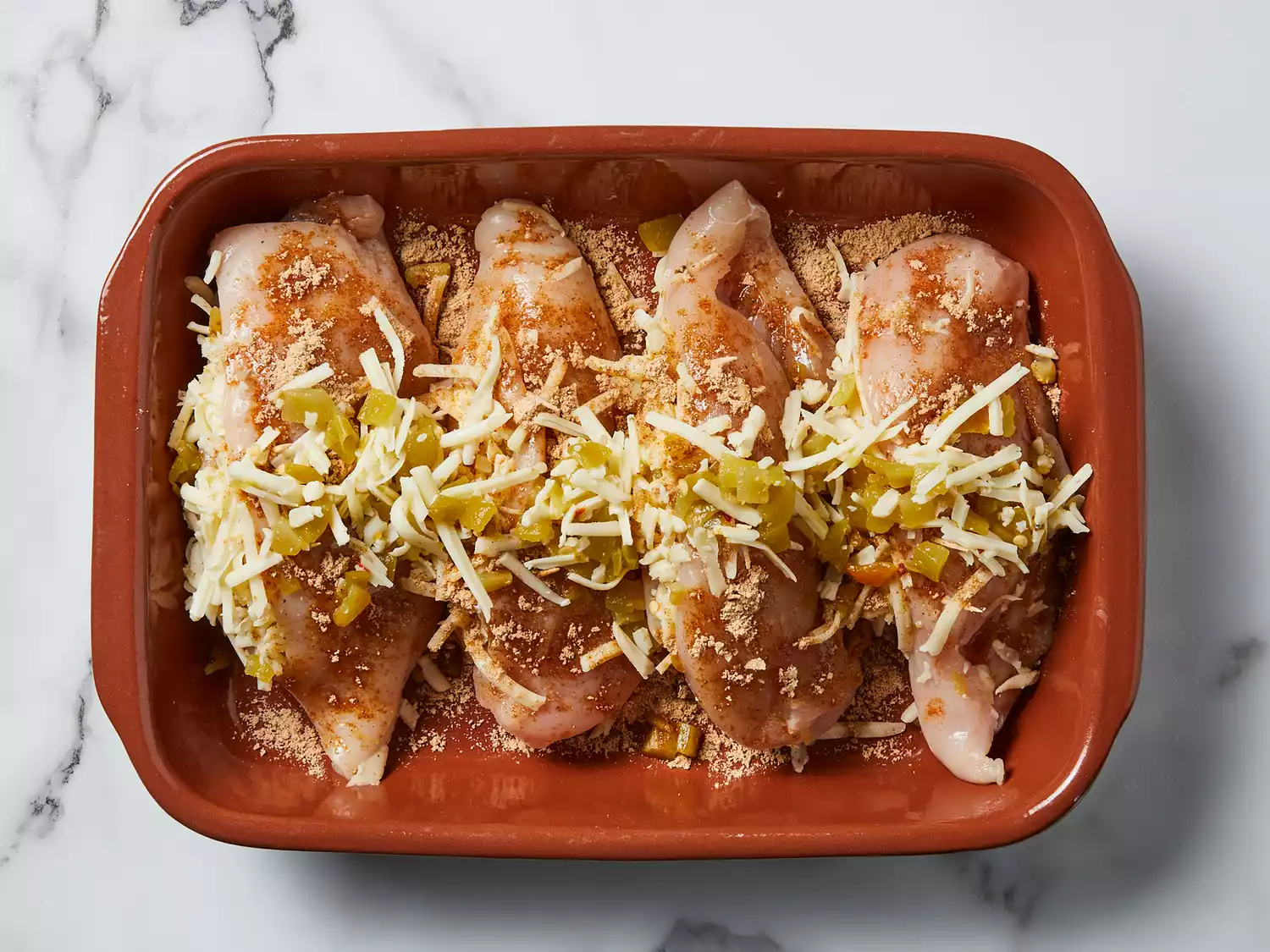 Chicken placed in baking dish and sprinkled with fajita seasoning, remaining cheese and chilies.