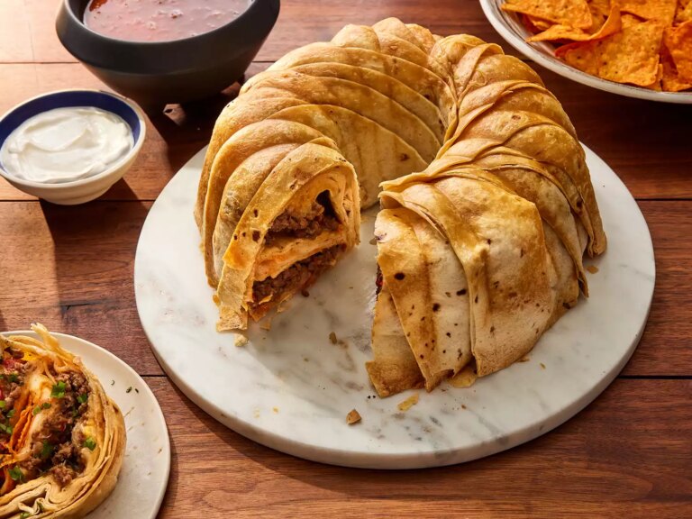 A high angle view of a crunchwrap ring made in a bundt pan and filled with layers of seasoned beef, nacho cheese, and crunchy chips, all wrapped in tortillas