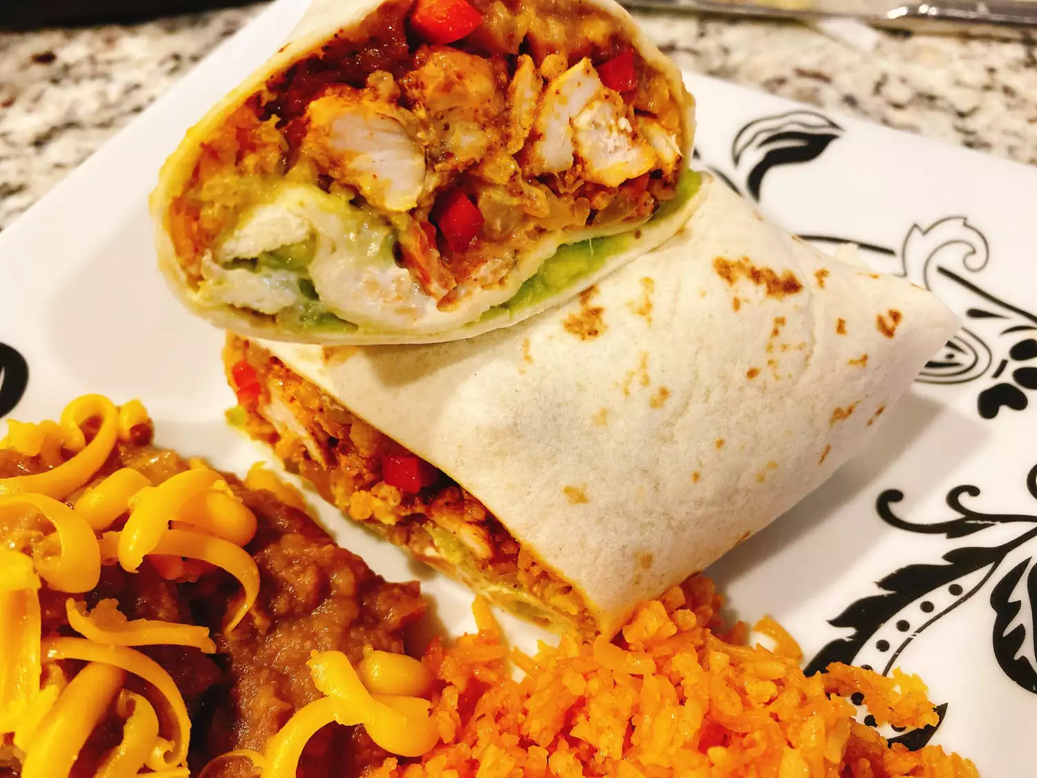 Chicken fajita burrito halved on a plate