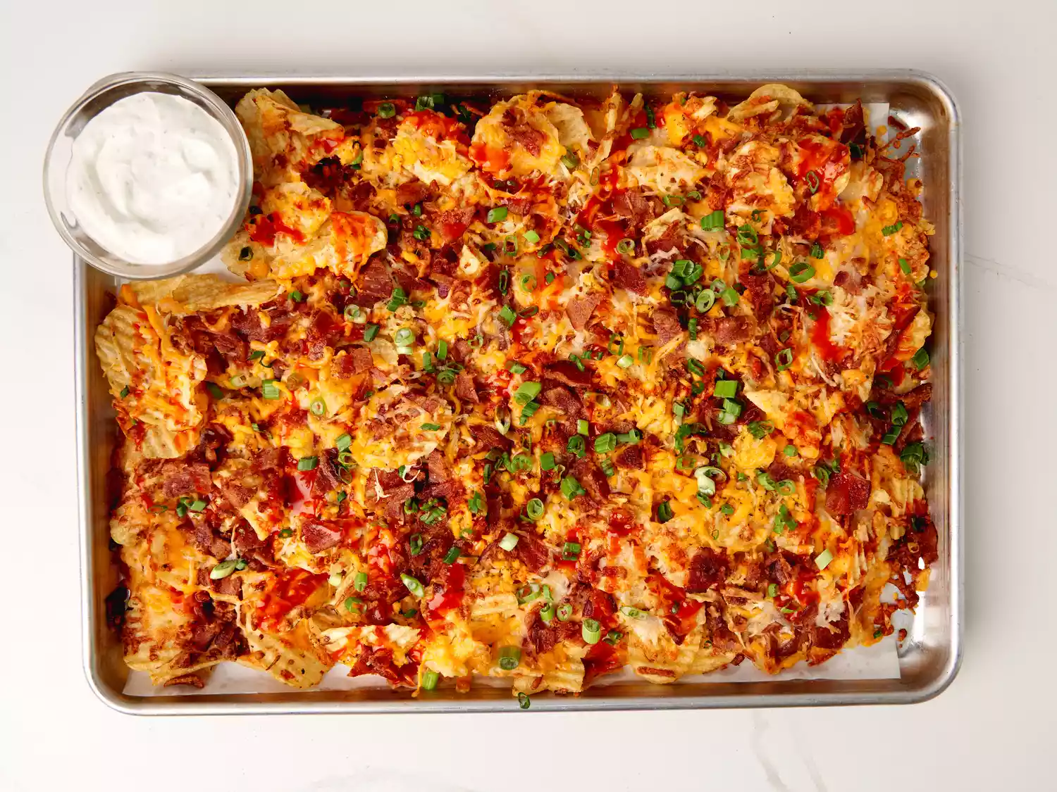 Overhead view of sheet pan with potato chip nachos and dipping sauce