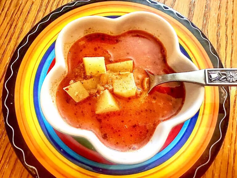 Bird's eye view of bowl of chorizo soup with potatoes on colorful charger