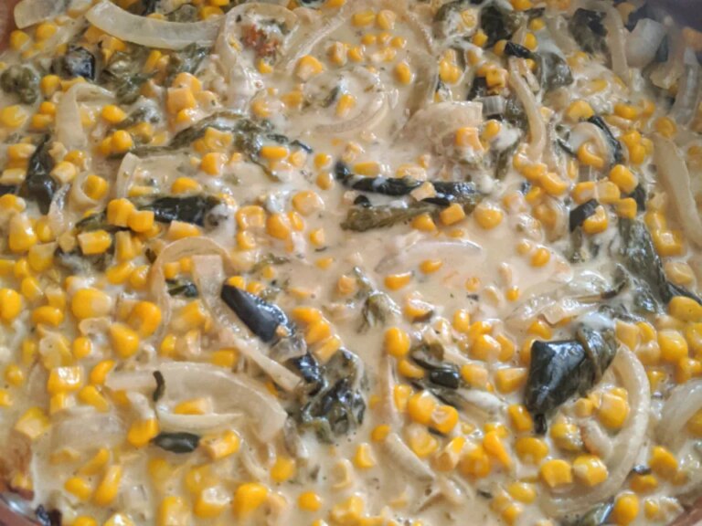 Close up view of rajas con crema, elote, y queso (creamy poblano peppers and sweet corn) in a pan