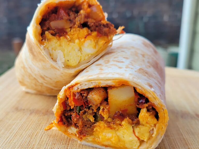 Split burrito with chorizo and scrambled eggs stacked on board