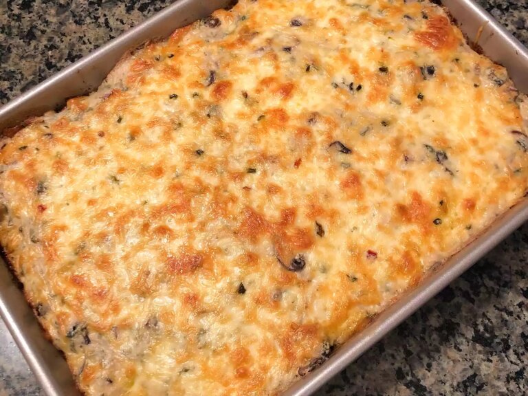 Close up view of a poblano chicken enchilada casserole with melted cheese on top, in a baking dish