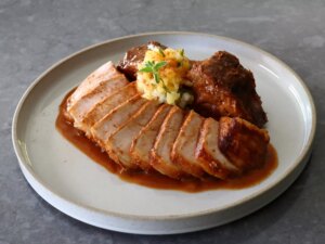 Sliced pork chop plated with pineapple salsa and chile marinade sauce