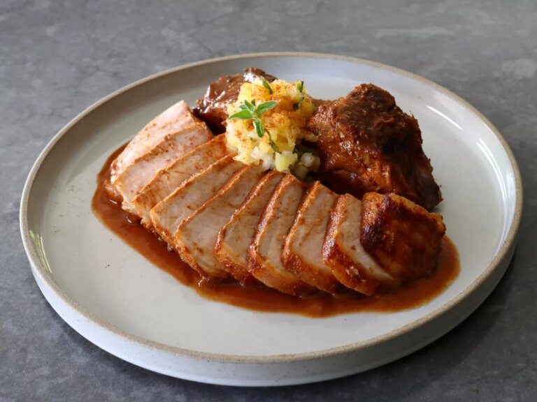 Sliced pork chop plated with pineapple salsa and chile marinade sauce