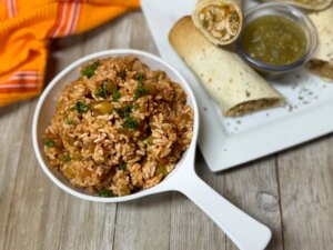 White ceramic pan with mexican rice, burritos in background