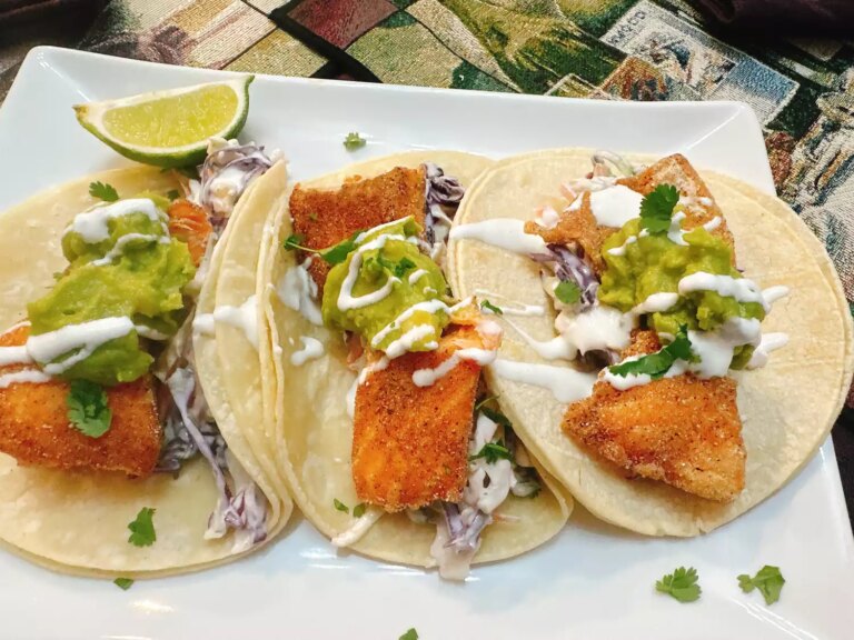 3 fried trout tacos with guacamole and slaw on white square plate